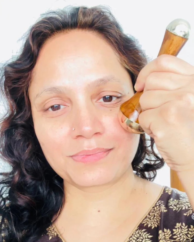 Mulher massageando o rosto com Kansa Wand massageador indiano ayurvédico para pele mais jovem