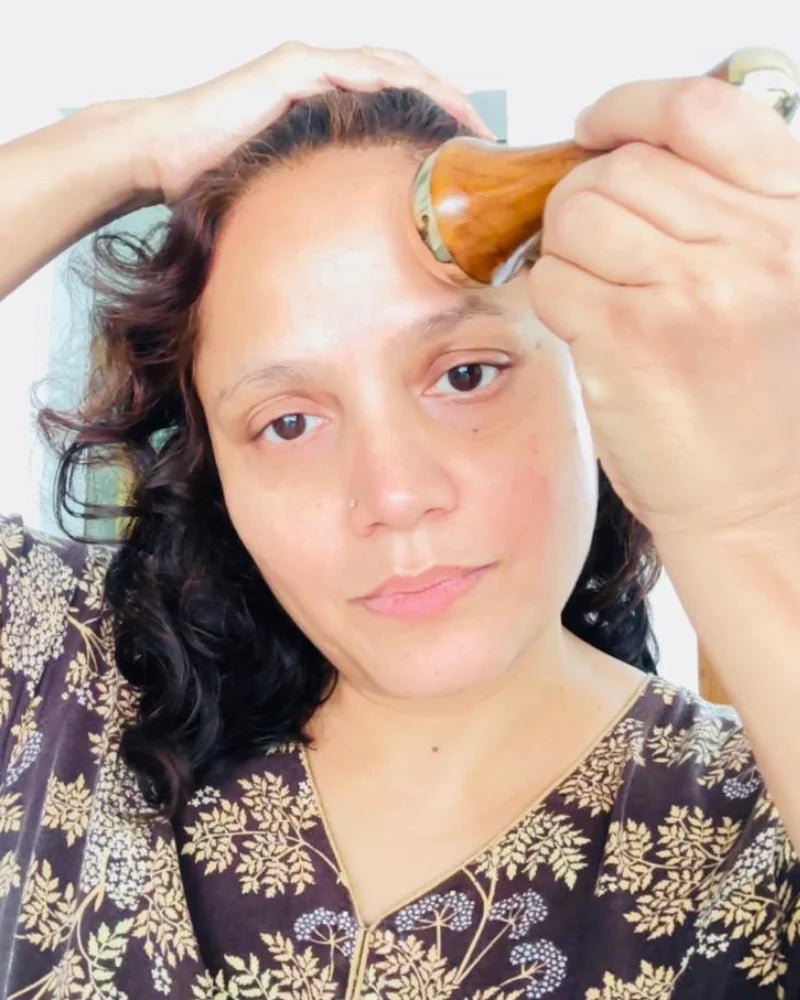 Mulher massageando o rosto com Kansa Wand instrumento massageador para pele macia, jovem