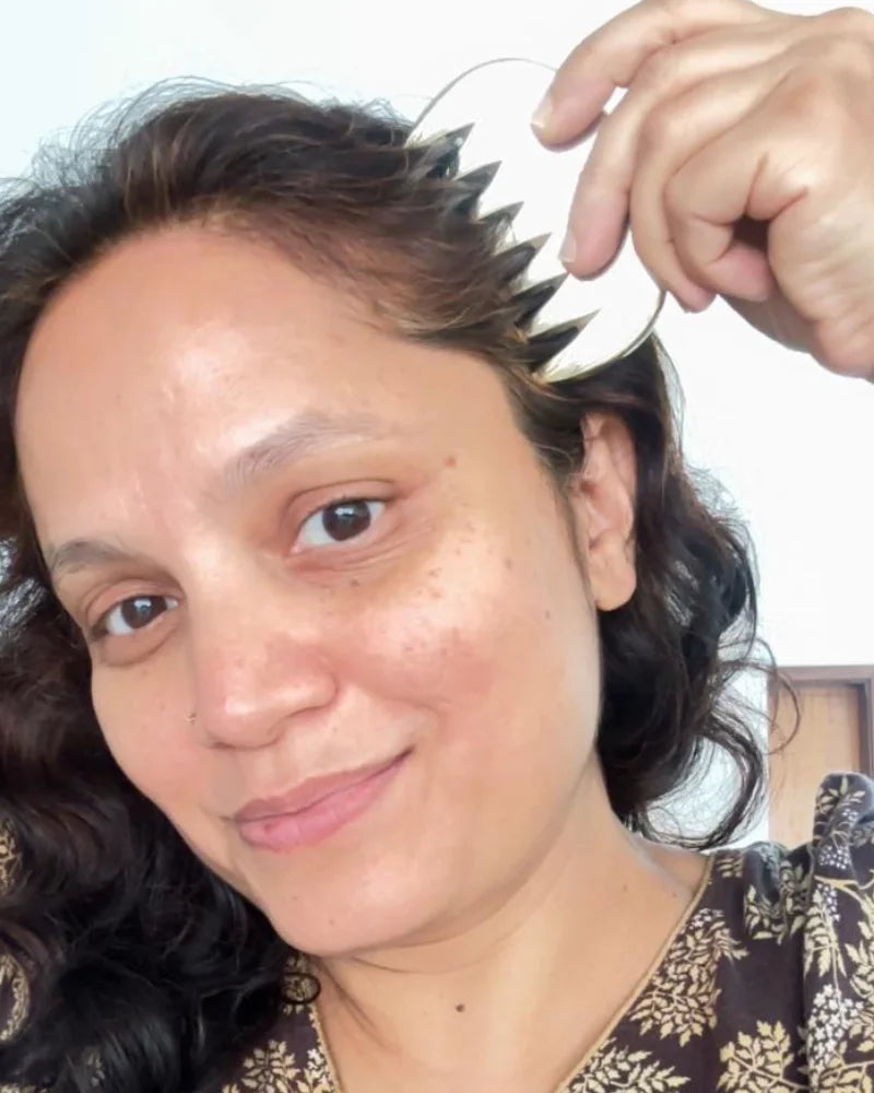Mulher masasageando couro cabeludo com pente massageador